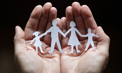 ritaglio di carta che rappresenta una famiglia racchiuso tra le mani