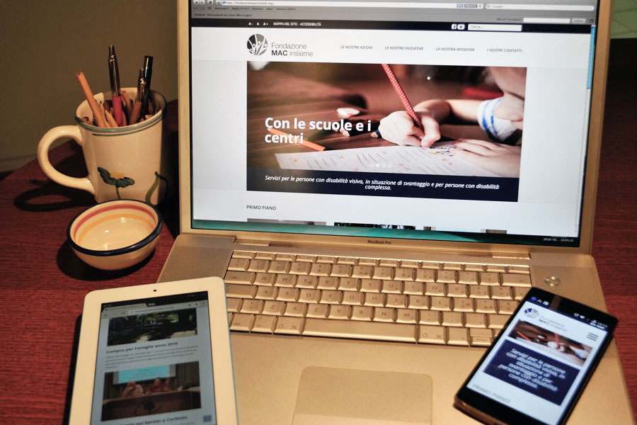 postazione da ufficio con un notebook, uno smartphone e un tablet tutti aperti sul sito della fondazione